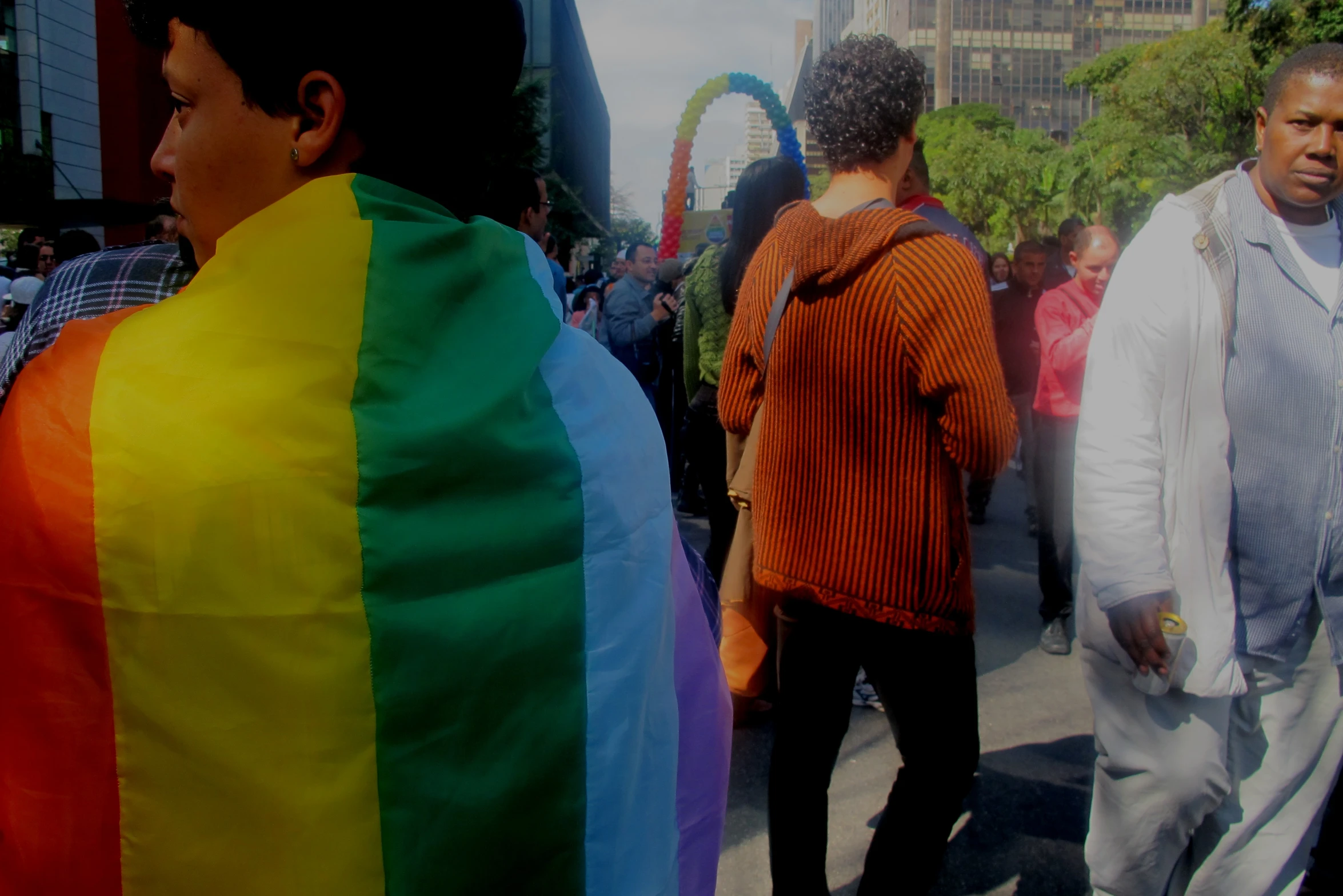 a man standing in the middle of a crowd with a rainbow flag