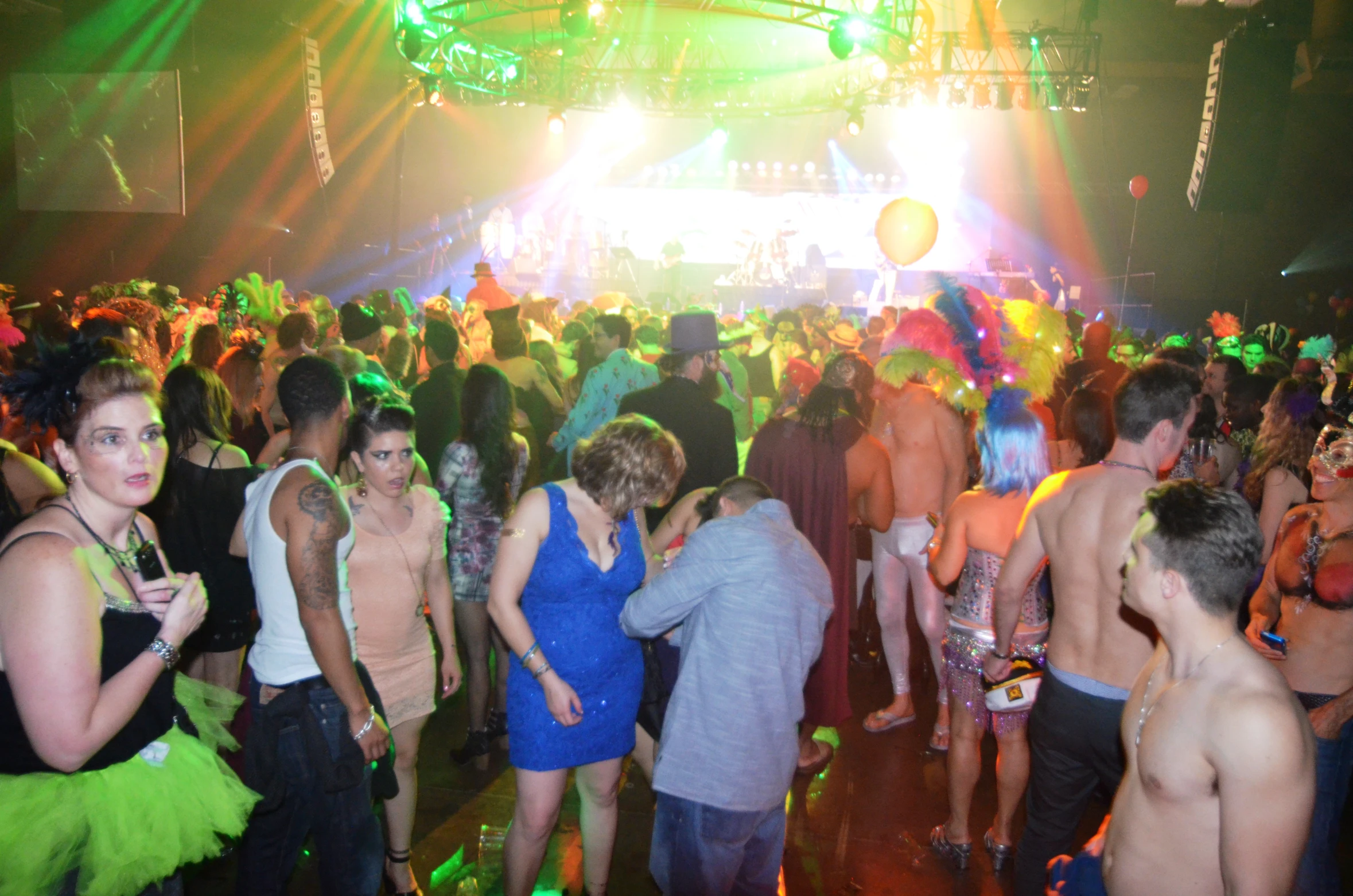 a crowd at a party with colored lights and dancers