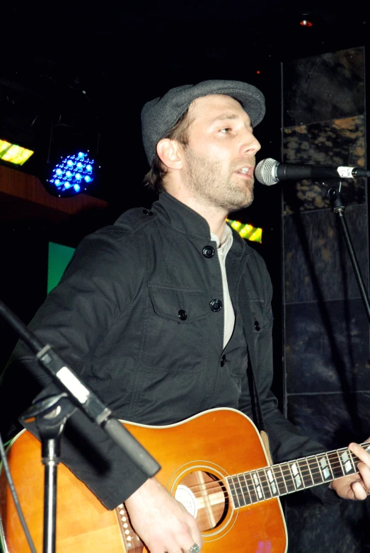 a man singing into a microphone while holding an acoustic guitar