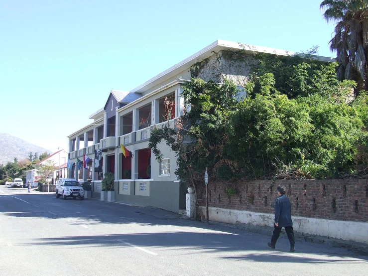 a man walking past an apartment building next to palm trees