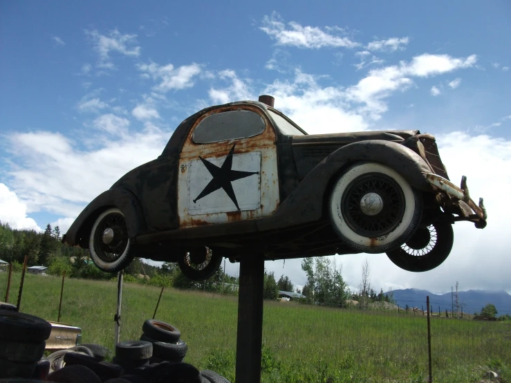 an antique car sculpture standing out in a field