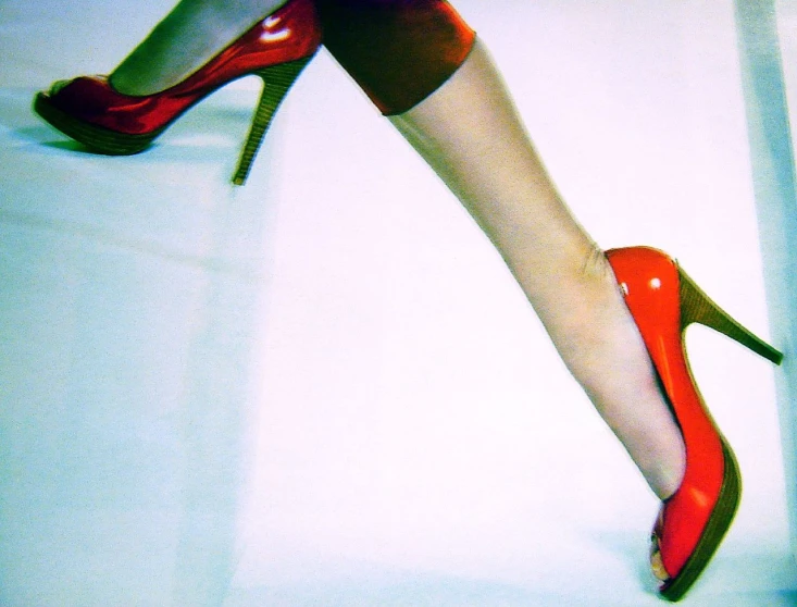 the legs of a woman in red high heels are shown