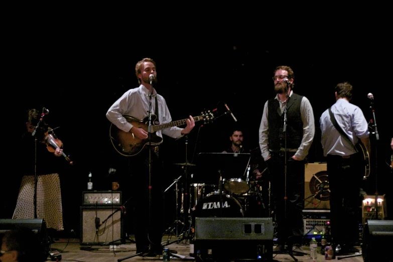 men sing and play music at a band performing on stage