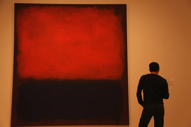 a man looking at a large art work in an exhibit