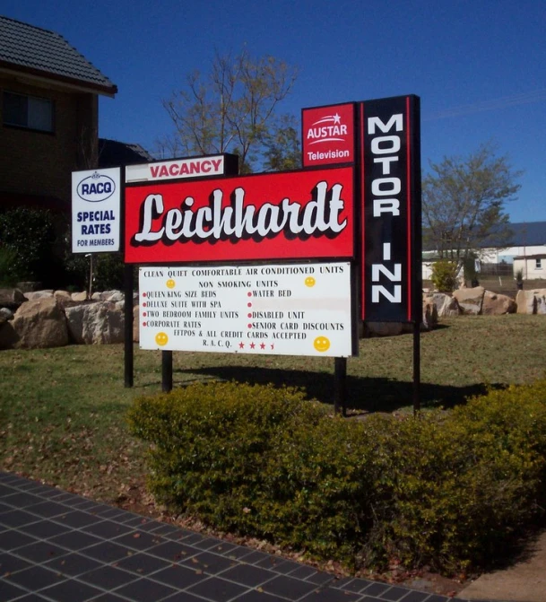 two signs are seen on the grass in front of a house