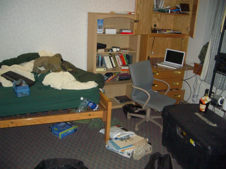 a messy bed in the corner of an otherwise used bedroom