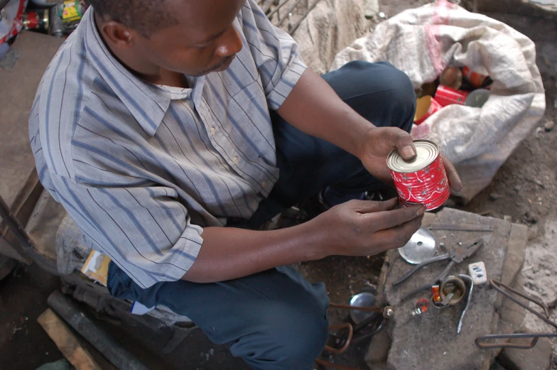 a man sitting down and holding onto a can of coke