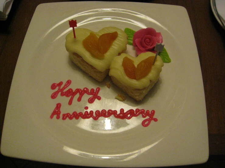 two small slices of heart shaped bread with hearts on them, in front of the words happy anniversary