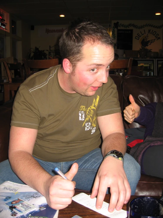 a man sits at a table writing on a piece of paper