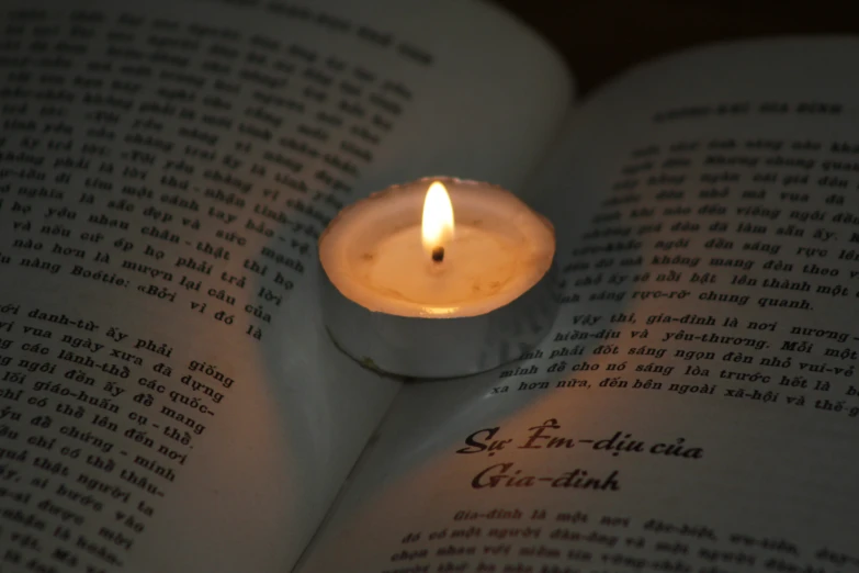 an open book with a lit candle sitting on top