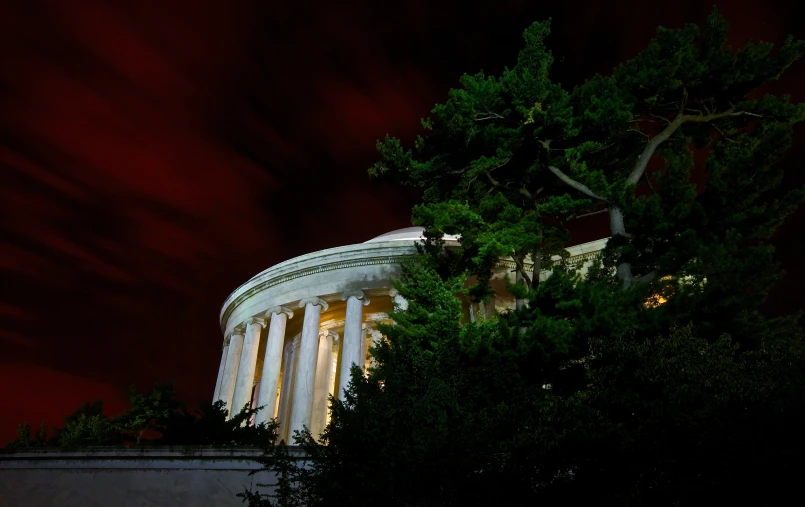 a tree is silhouetted against a dark sky above a white building