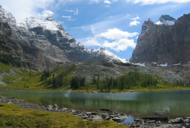 a lake near some rocky mountains under a cloudy sky