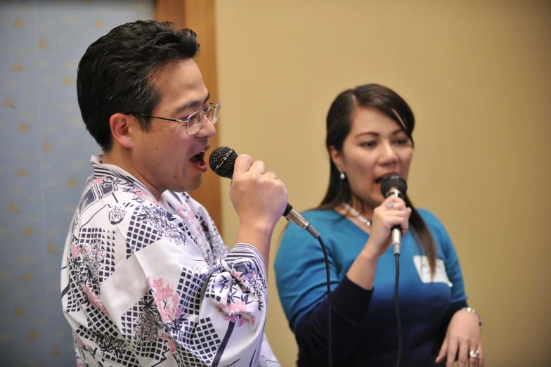 two people singing into a microphone in front of a microphone