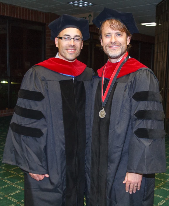 two people standing near each other in caps and gowns