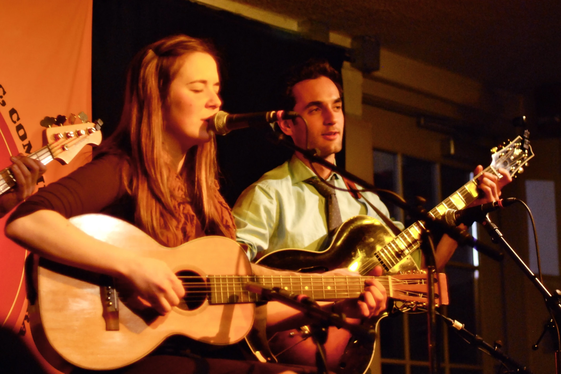 two people are playing guitars on a stage