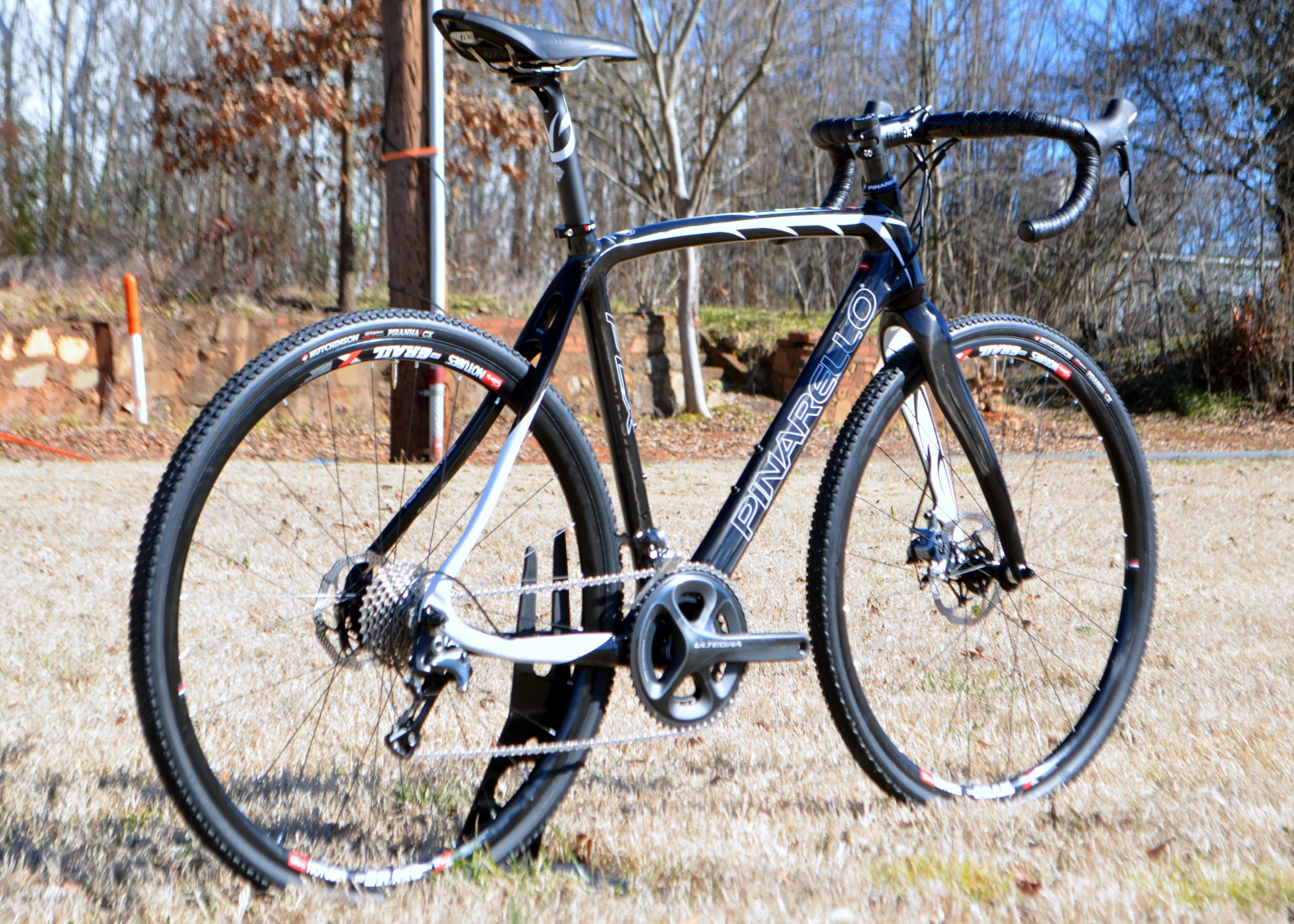 a black road bike parked in a field with trees and brown grass