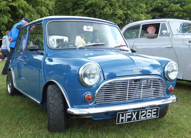 a blue mini car parked in a field with others