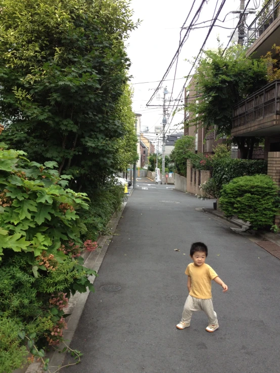 a small boy is walking down a narrow alley way