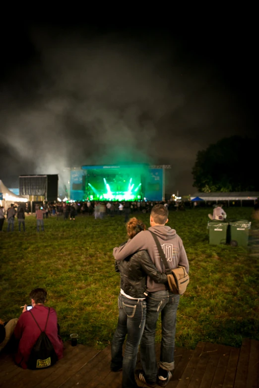 two people are standing together in front of a stage