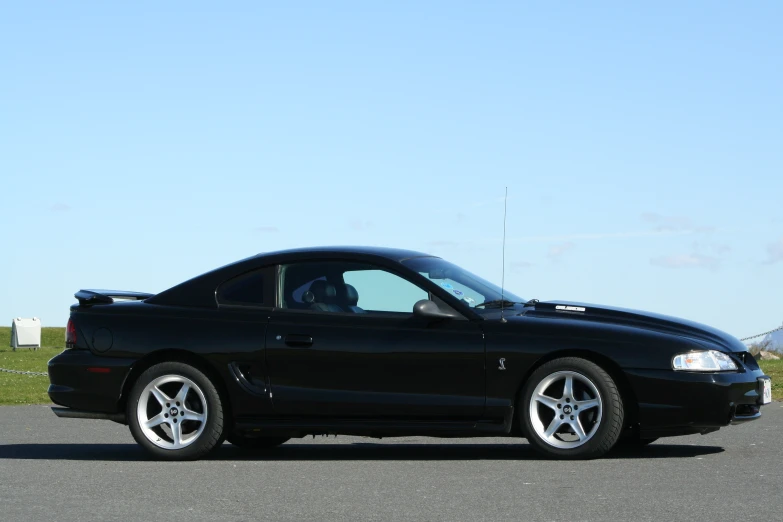 black sports car sitting on the pavement in parking lot