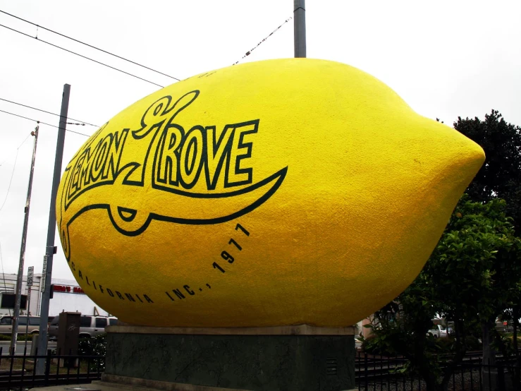 a big lemon shaped statue sits on a plaza