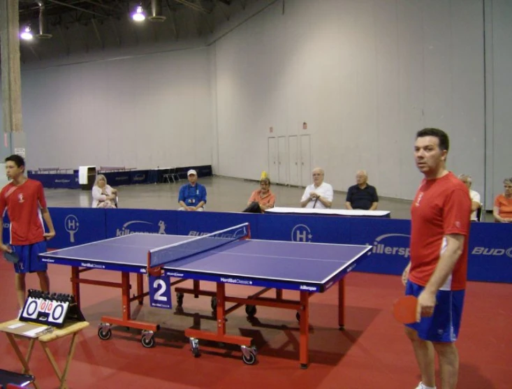 a ping pong table and two tennis tables with the same racket as others on the sidelines