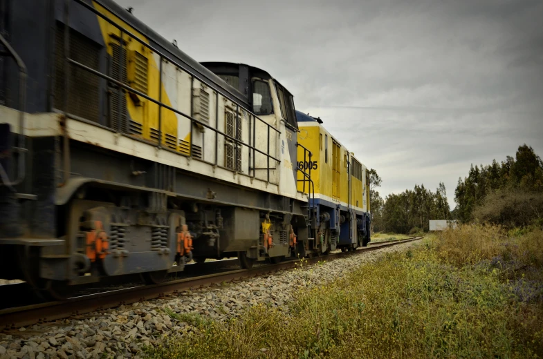 a train that is going by some grass and rocks