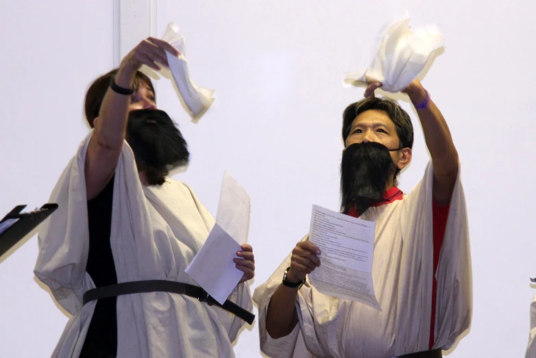 two people with beards and capes holding paper
