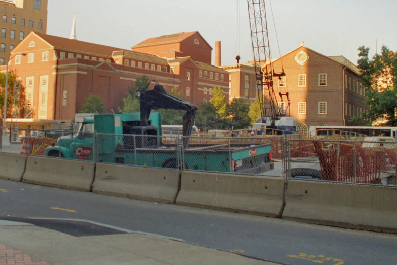 a large crane near some construction trucks and buildings