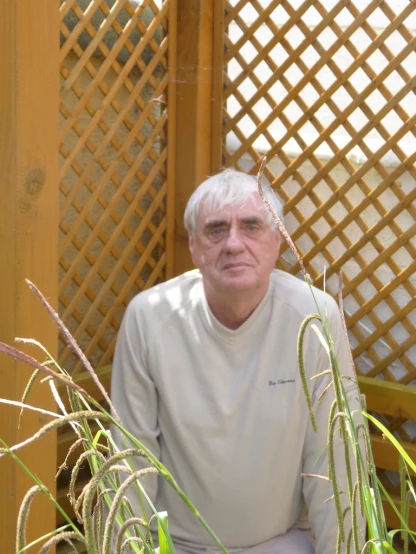 a man in glasses is sitting by some grass