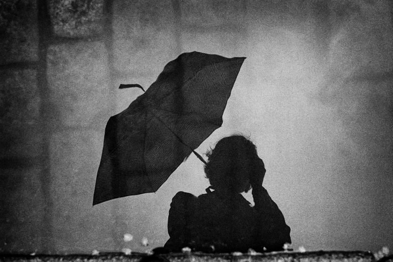 woman with umbrella standing next to large mirror