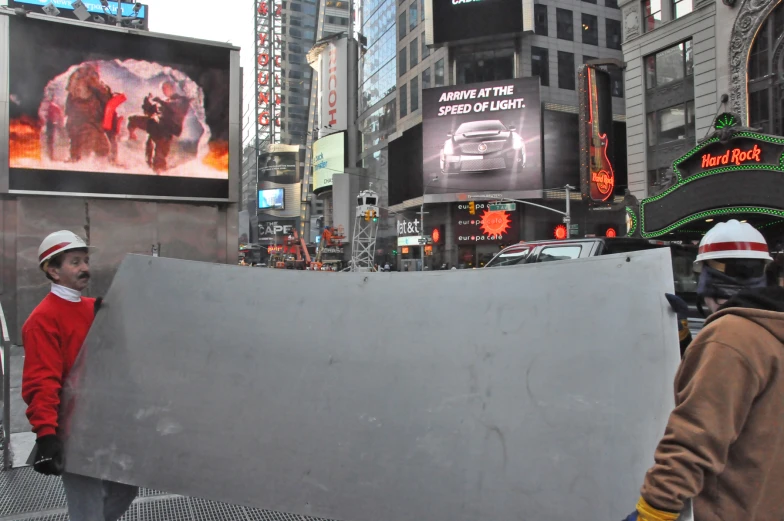 two men holding a large wall of cement on a street