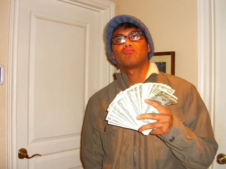 a man with a blue hat holding stacks of money