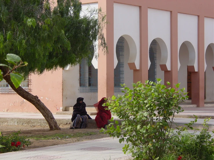 a couple of people standing near a big pink building