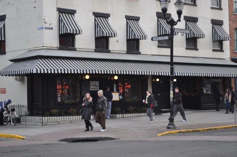 two people walking along the sidewalk next to a building