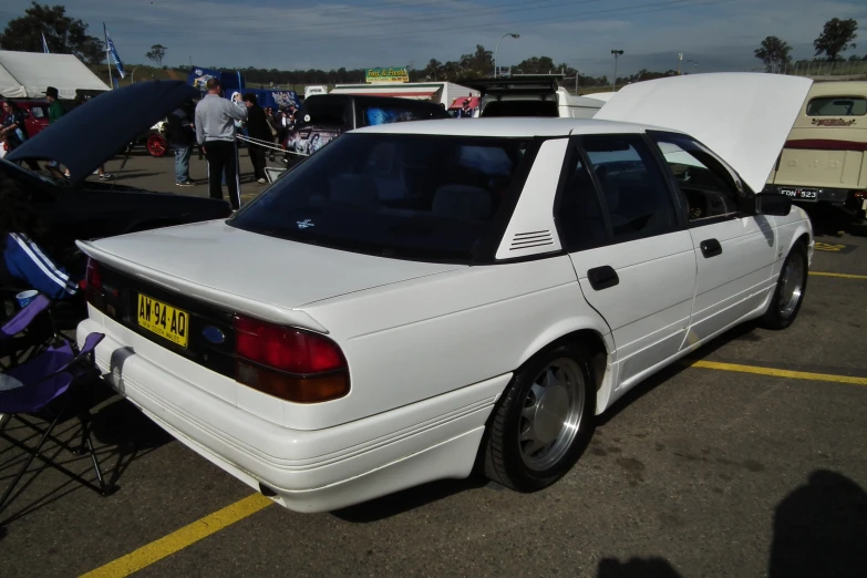 an older model white car is parked in a lot