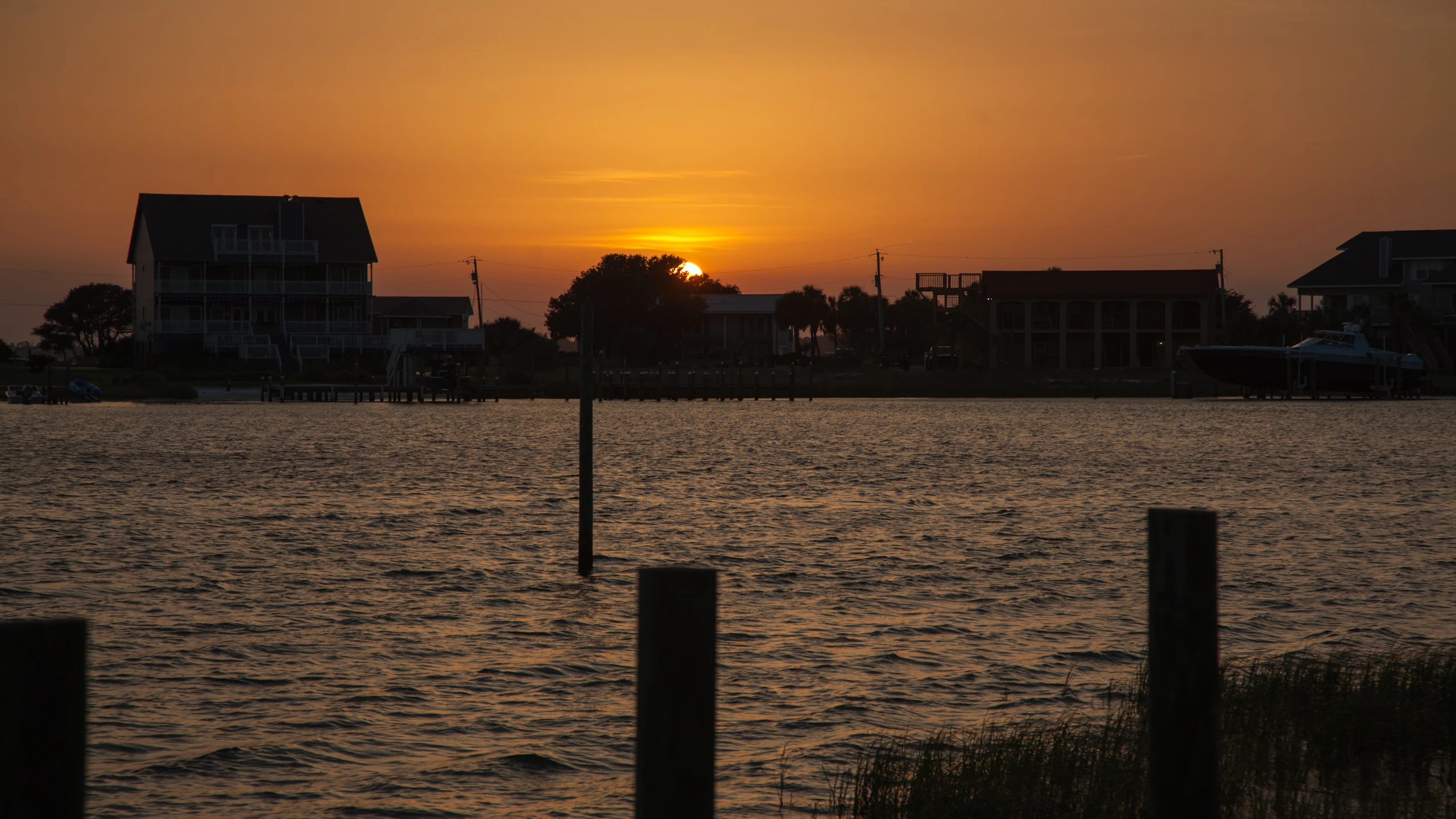 a sunset reflecting off the water with houses in the background