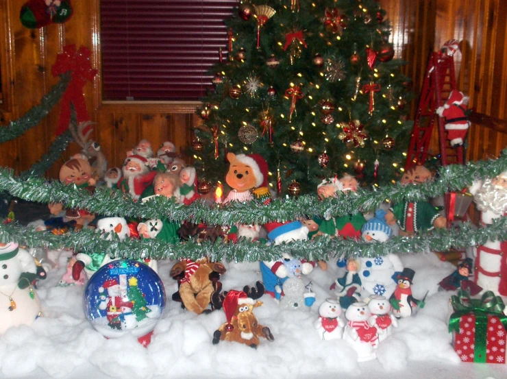 a snow covered shelf and christmas decorations with a christmas tree in the background