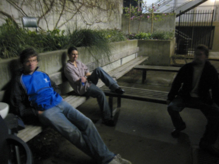 three men sitting on a bench in a city