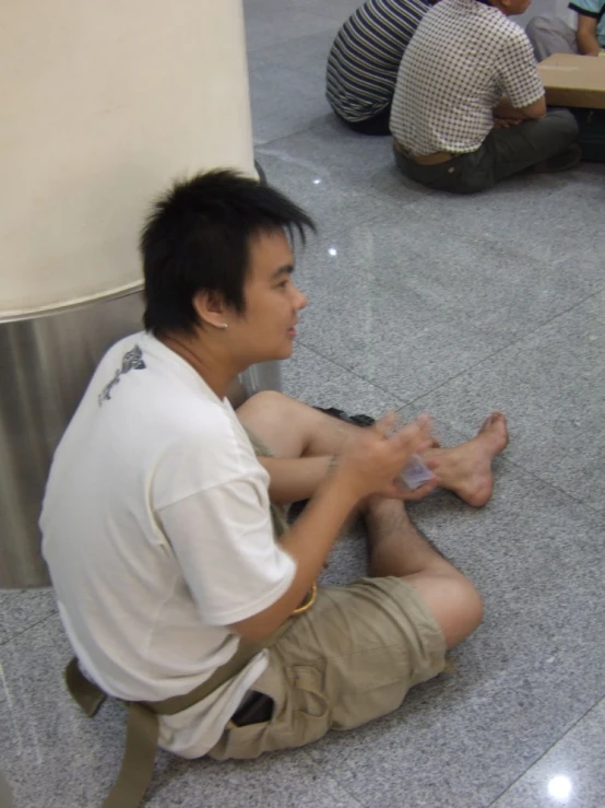 a man sitting in the middle of a room on his feet with a phone