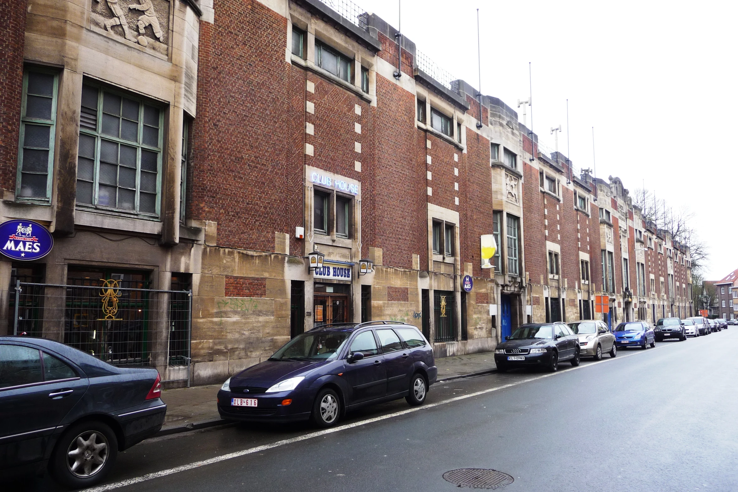 a long street lined with parked cars next to tall buildings