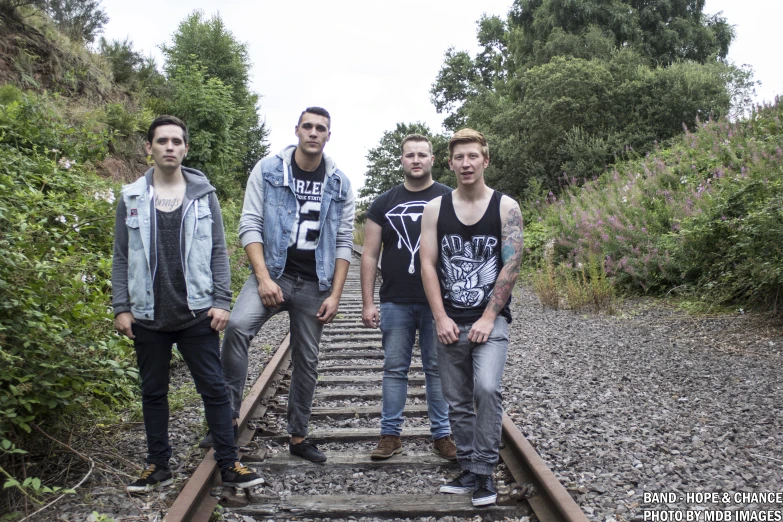 four men standing on train tracks outside on their side