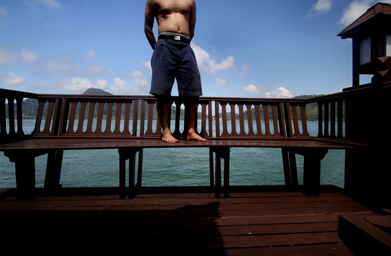 a man standing on top of a bench next to water