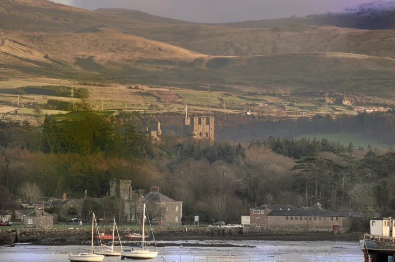 three boats are in the water with some buildings in the background