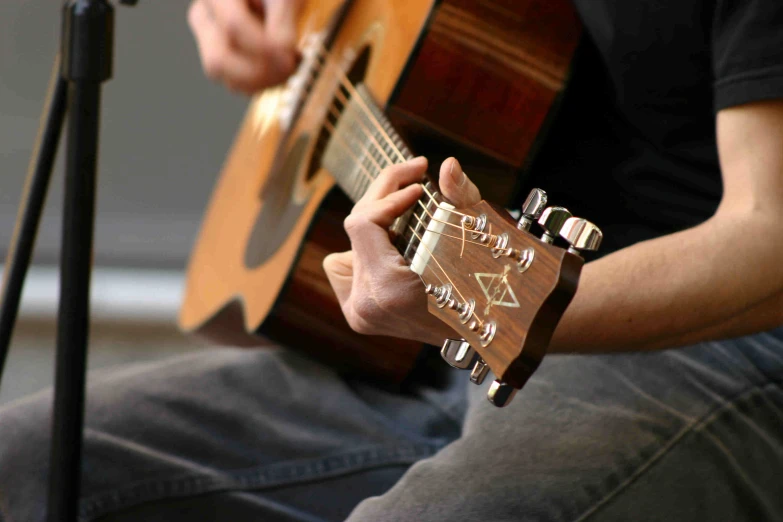 man playing guitar close up on a wooden chair