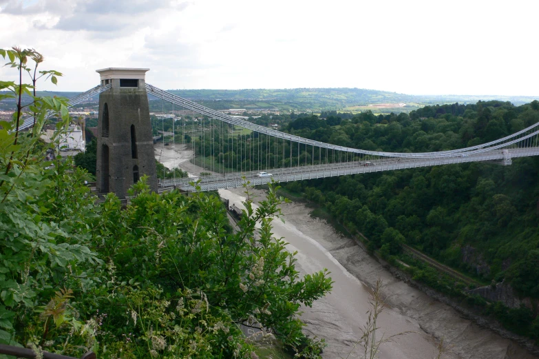 a suspension bridge over the river in a forested area