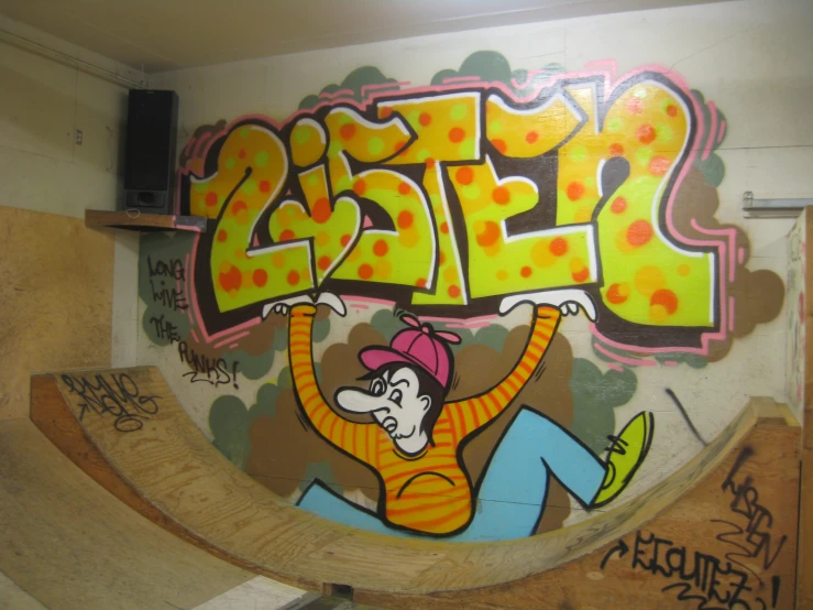 a skate board ramp decorated with graffiti and a guy holding a sign