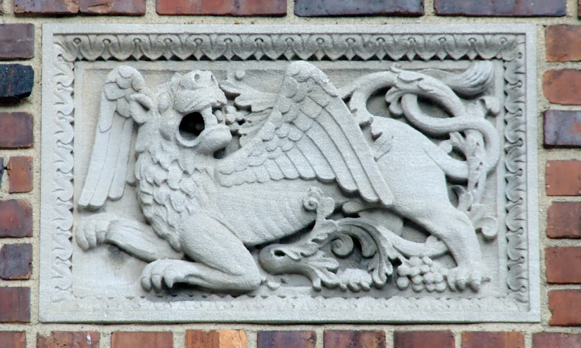 a lion's head and two lions on a brick wall