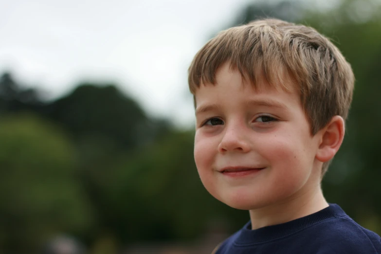 a smiling child in a blue shirt looking straight ahead