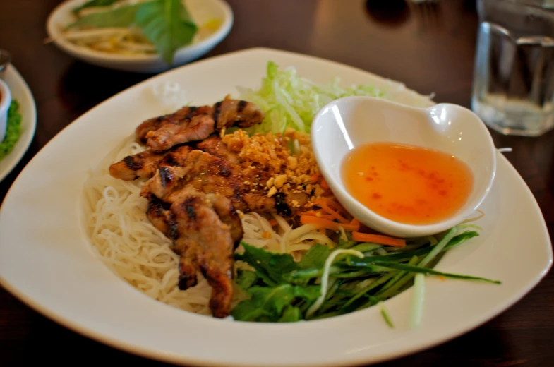 a plate with noodles, meat and sauce in it